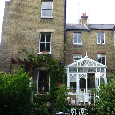 the rear of an old building with a glass conservatory